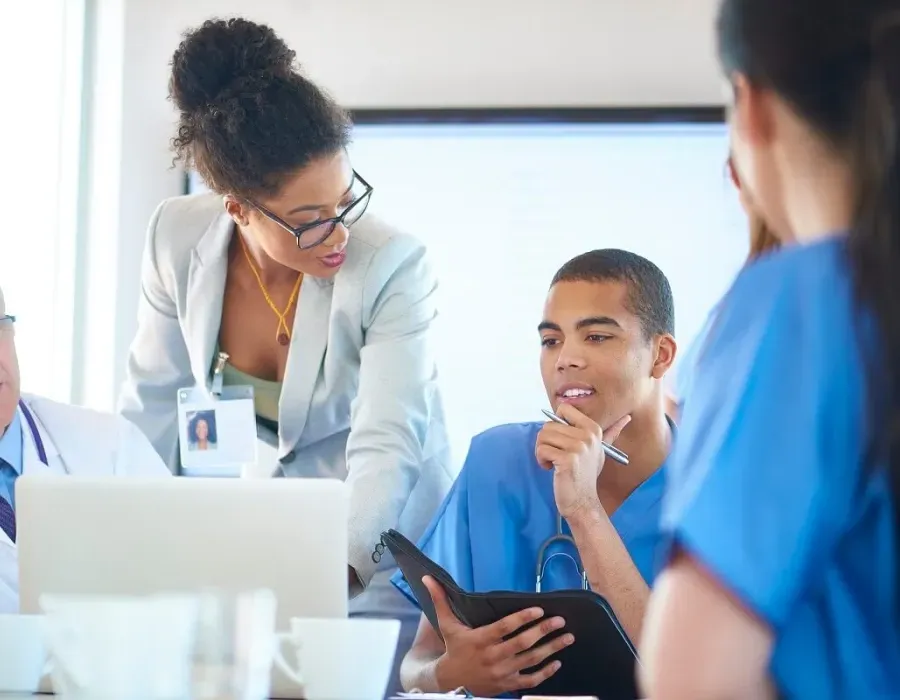 Nurse administrator speaking with other healthcare managers during team meeting